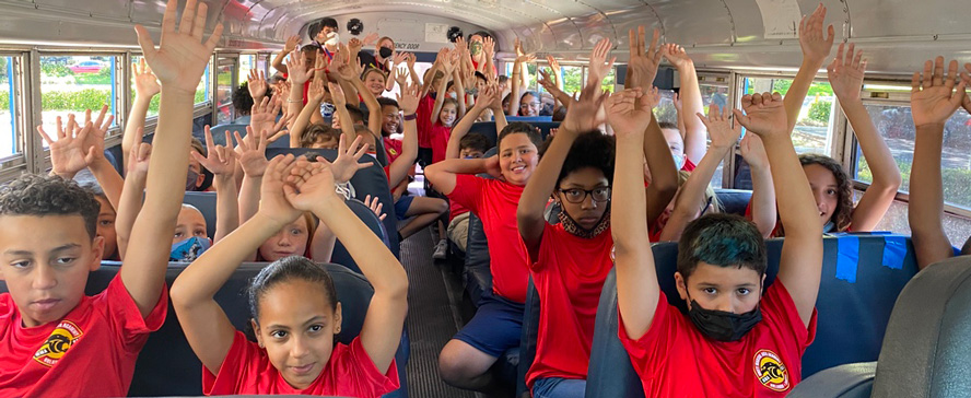 bus-hands-high martial arts summer camp group on field trip
